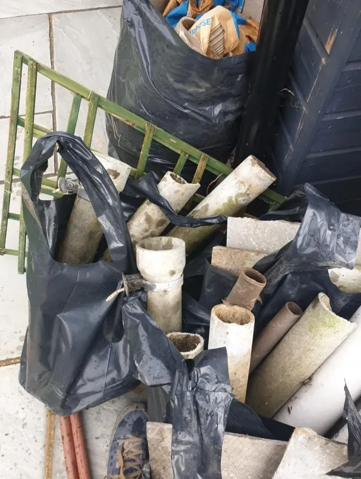 Asbestos materials being placed in black bags for safe disposal by Stay Safe Environmental