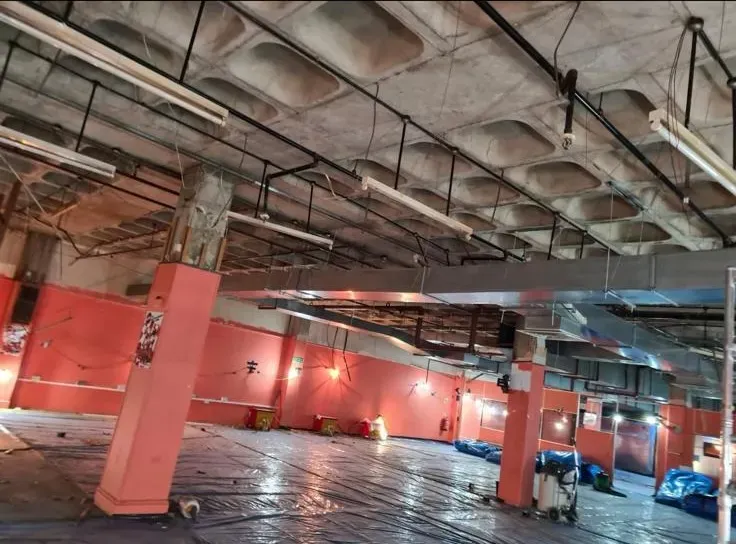 Large commercial interior prepared for asbestos removal with protective plastic sheeting on the floor